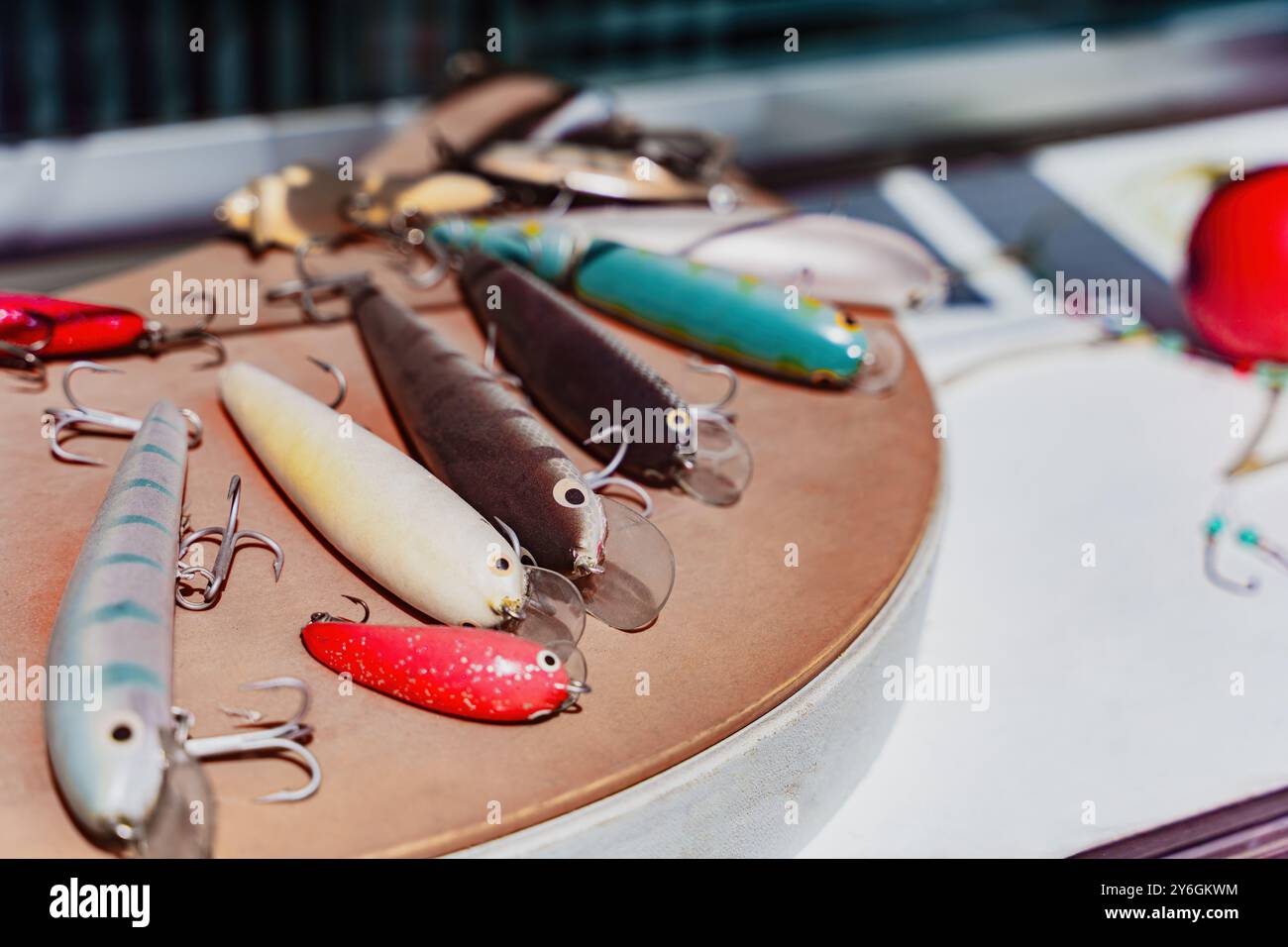 Le colorate lure da pesca con ganci sono disposte su un tavolo, attrezzi per i pescatori nella pesca d'acqua dolce e d'acqua salata Foto Stock