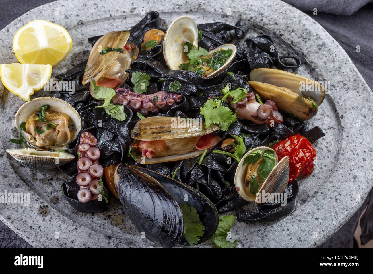 Cibo, frutti di mare fettuccine fehttuchini neri. Pasta nera con calamari, vongole di polpo, cozze su piatto di pietra. Piatto da buongustai Foto Stock