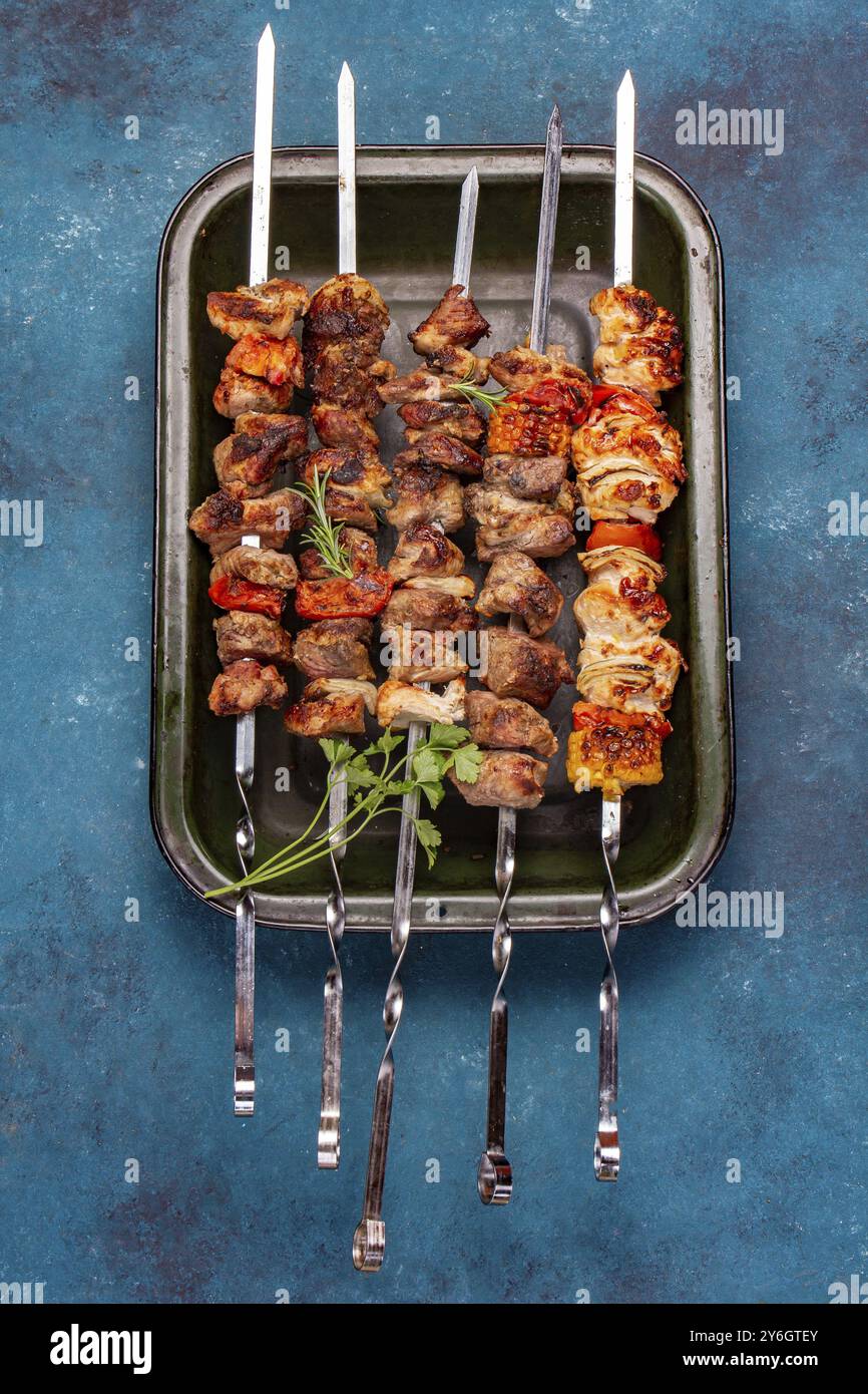 Cibo, cibo, carne di maiale grigliata barbecue, spiedini di pollo e verdure su vassoio Vista dall'alto, disposizione piatta. Sfondo blu Foto Stock