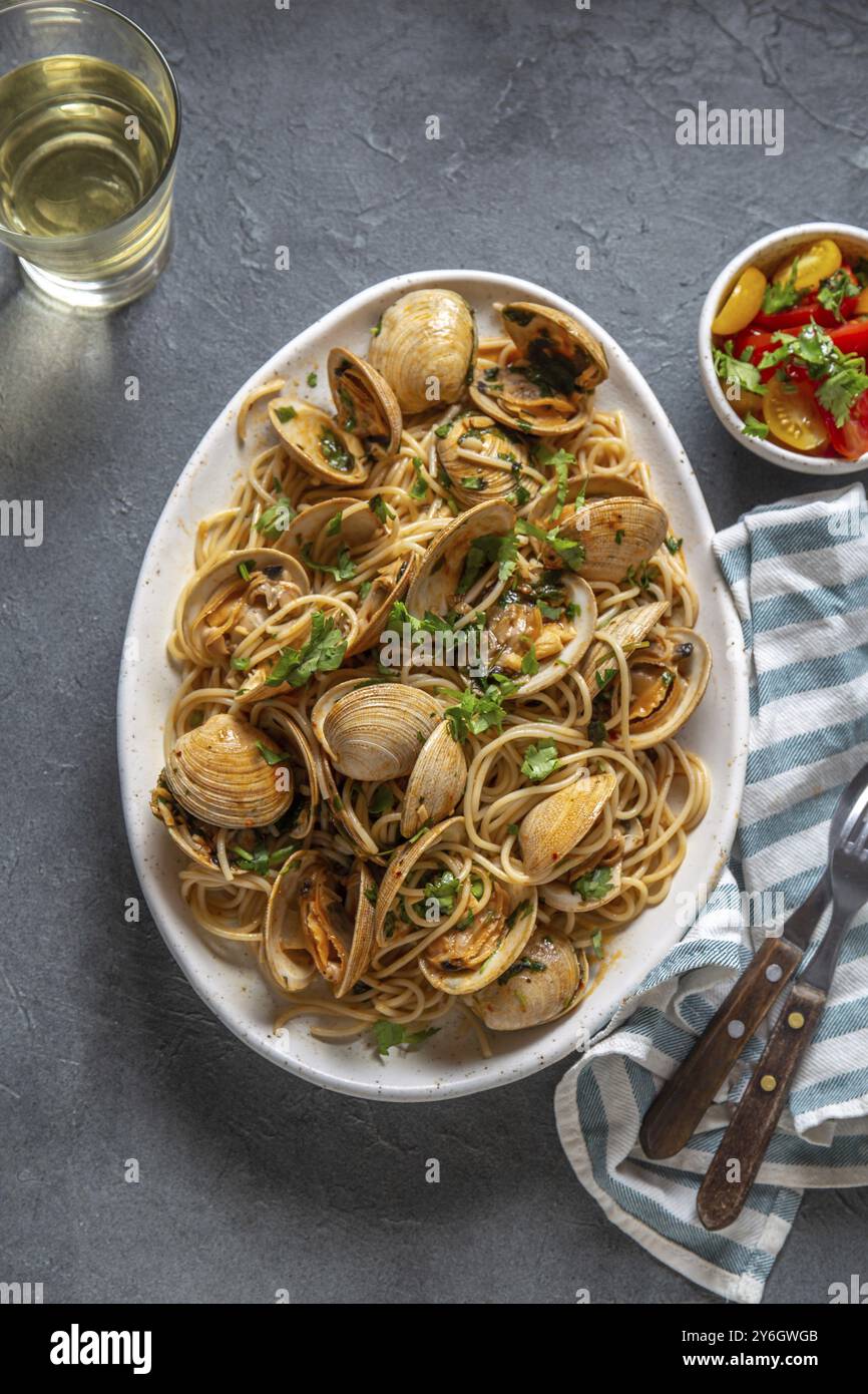 Cibo, cibo, pasta di pesce. SPAGHETTI ALLE VONGOLE ITALIANI. Spaghetti di vongole su piatto bianco con vino bianco, fondo grigio. Vista dall'alto Foto Stock