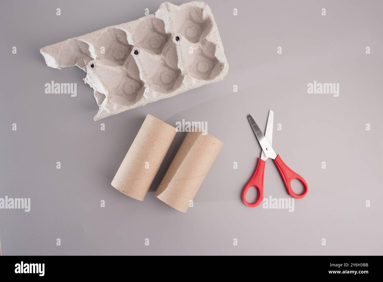 Forbici accanto al cartone per uova, oggetti di artigianato e materiali sostenibili. Pezzi in cartone pressofuso per creare e giocare da tavolo. oggetti in grigio, ispirazione Foto Stock