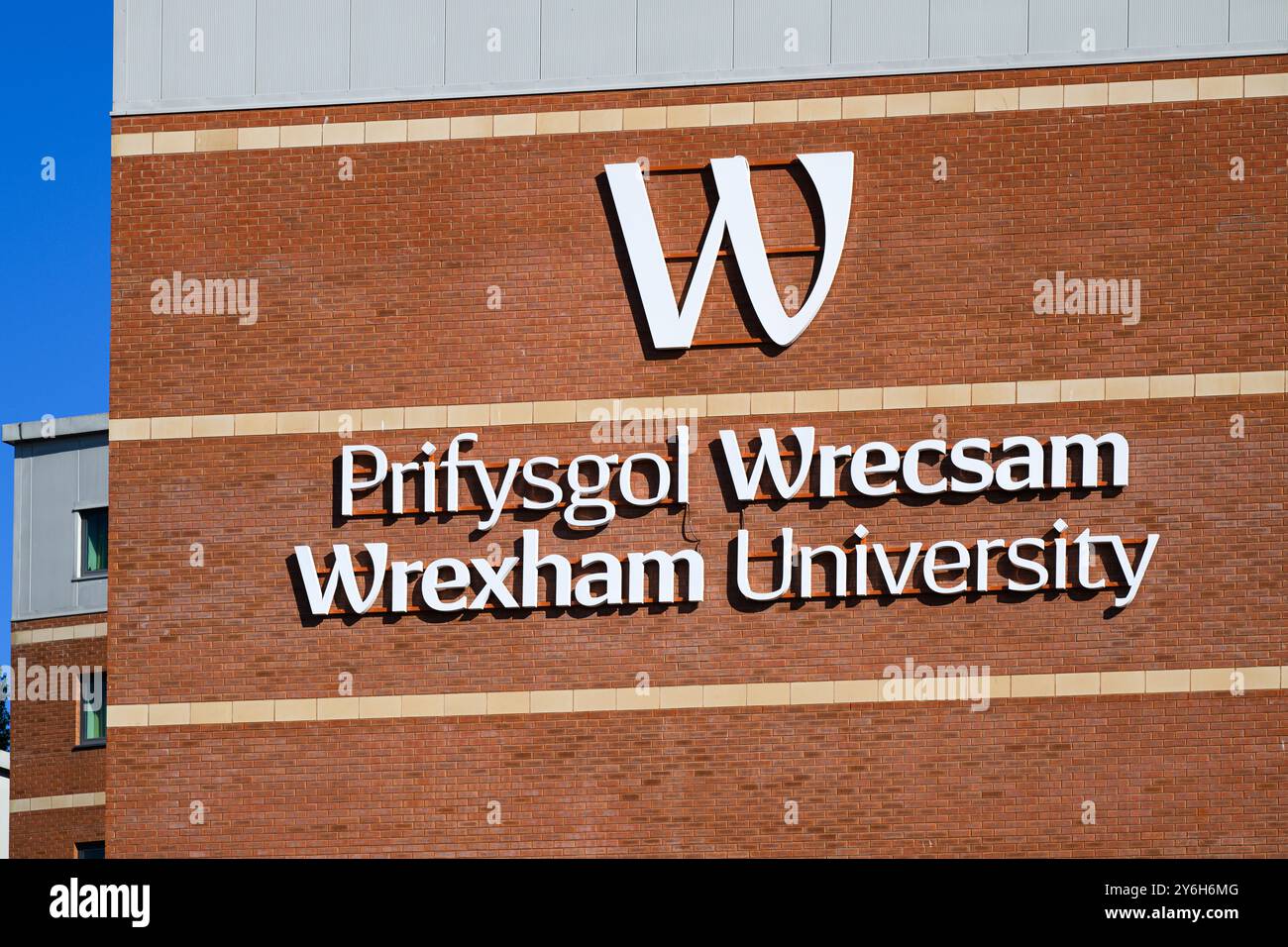 Wrexham, Galles, Regno Unito - 17 settembre 2024; firma con il logo della lettera sulla parete in mattoni rossi della Wrexham University in Galles Foto Stock