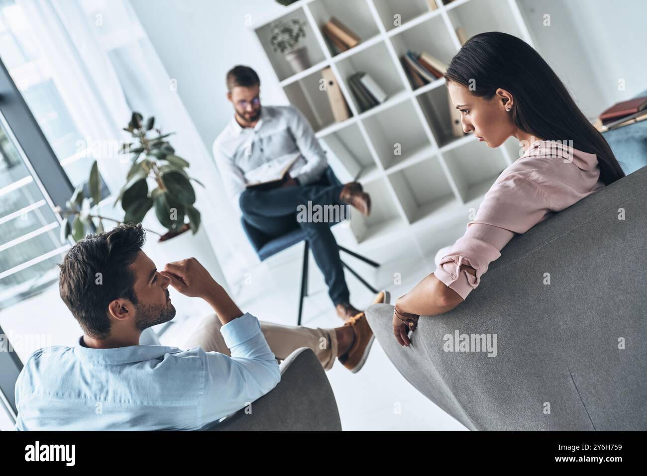 Aiutare gli altri. Giovane coppia sposata che parla mentre si siede alla sessione di terapia con lo psicologo Foto Stock