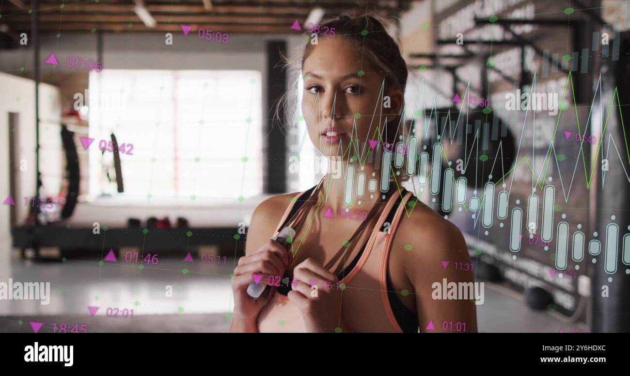 Immagine di tracciamento dei dati di fitness su una donna che tiene la corda per saltare in palestra Foto Stock