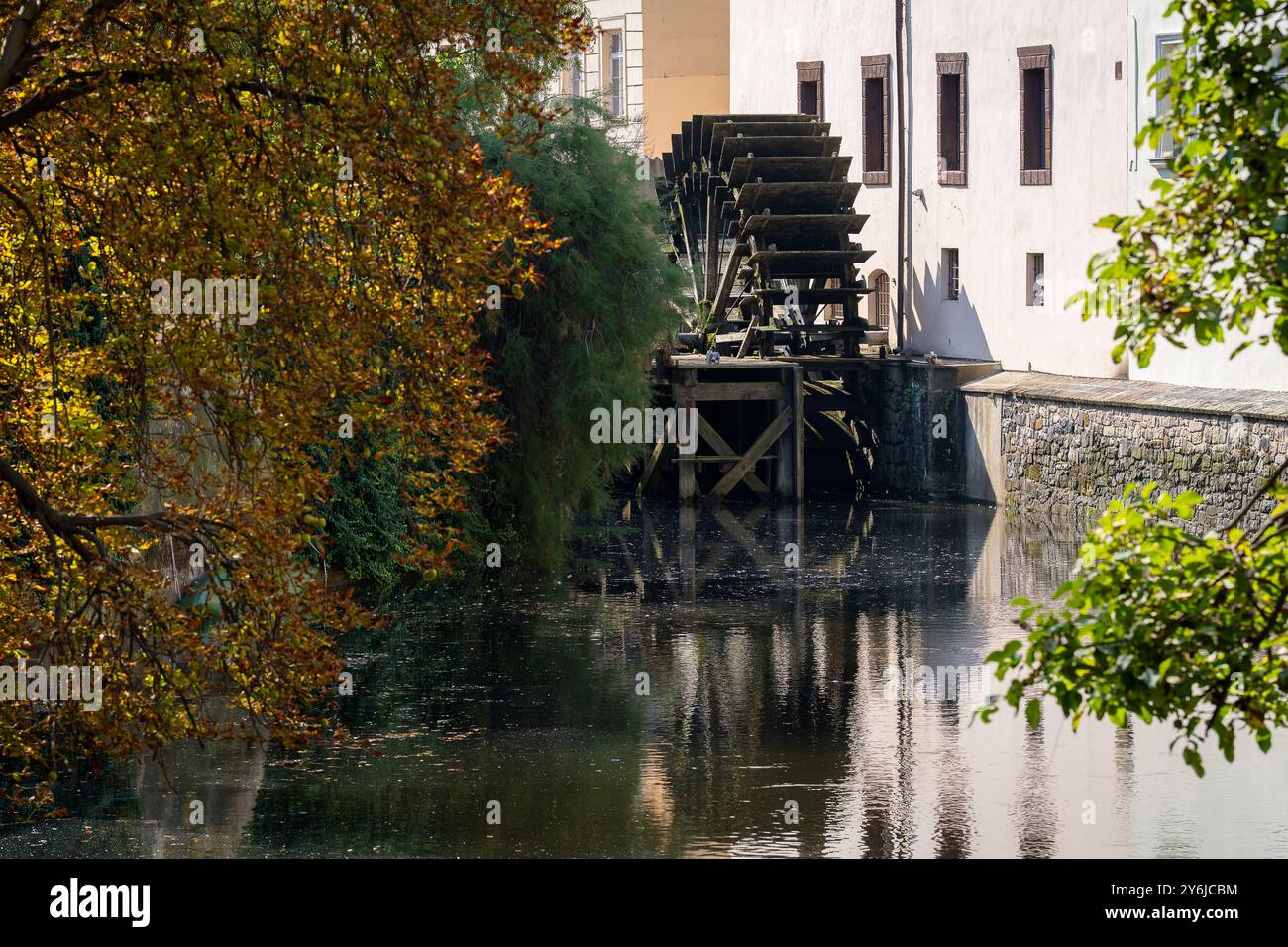 Vista della grande ruota di legno di un mulino ad acqua sul fiume Moldava nella città vecchia di Praga. Una passeggiata in città in un caldo e senza nuvole giorno d'autunno. Foto Stock