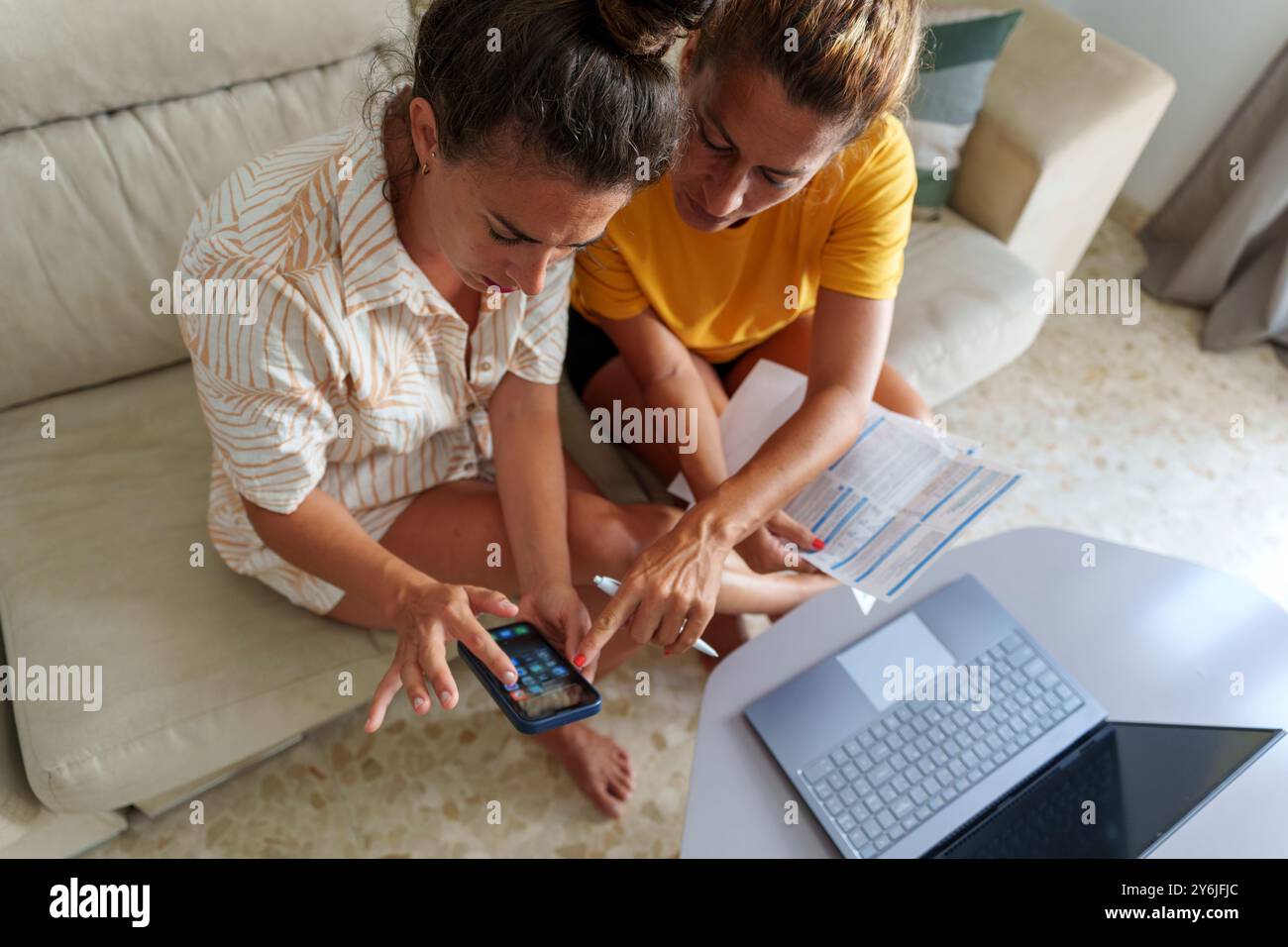Due donne coppia che rivede le bollette e i documenti finanziari insieme a casa Foto Stock