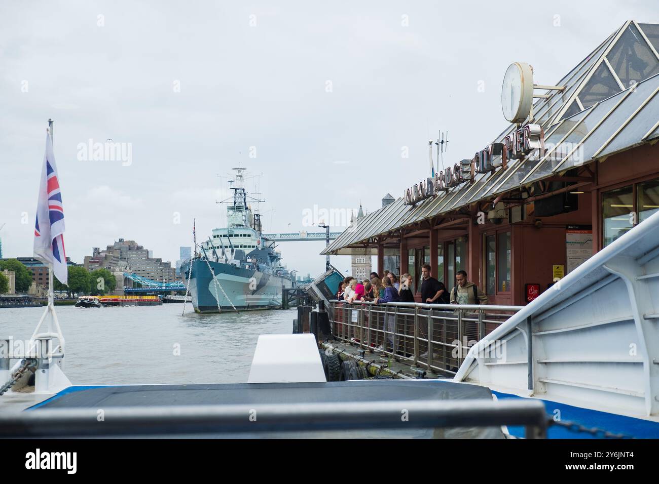 Londra, Regno Unito - 25 luglio 2024: Il battello Uber si ferma al molo di London Bridge City sul Tamigi. Bandiera della Gran Bretagna che sventola. Bandiera del Regno Unito in vento. Foto Stock