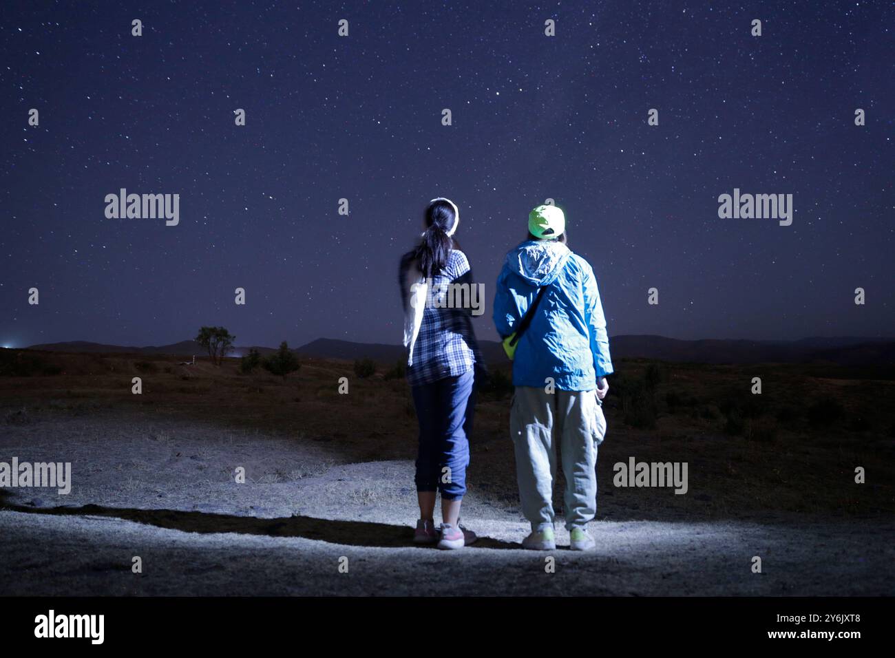 Due persone che guardano le stelle sotto un cielo notturno limpido in un luogo remoto. Foto Stock