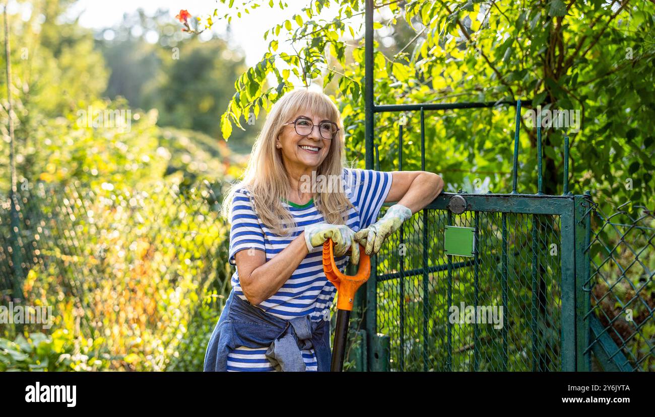 Donna anziana che lavora alla sua assegnazione in una giornata di sole Foto Stock