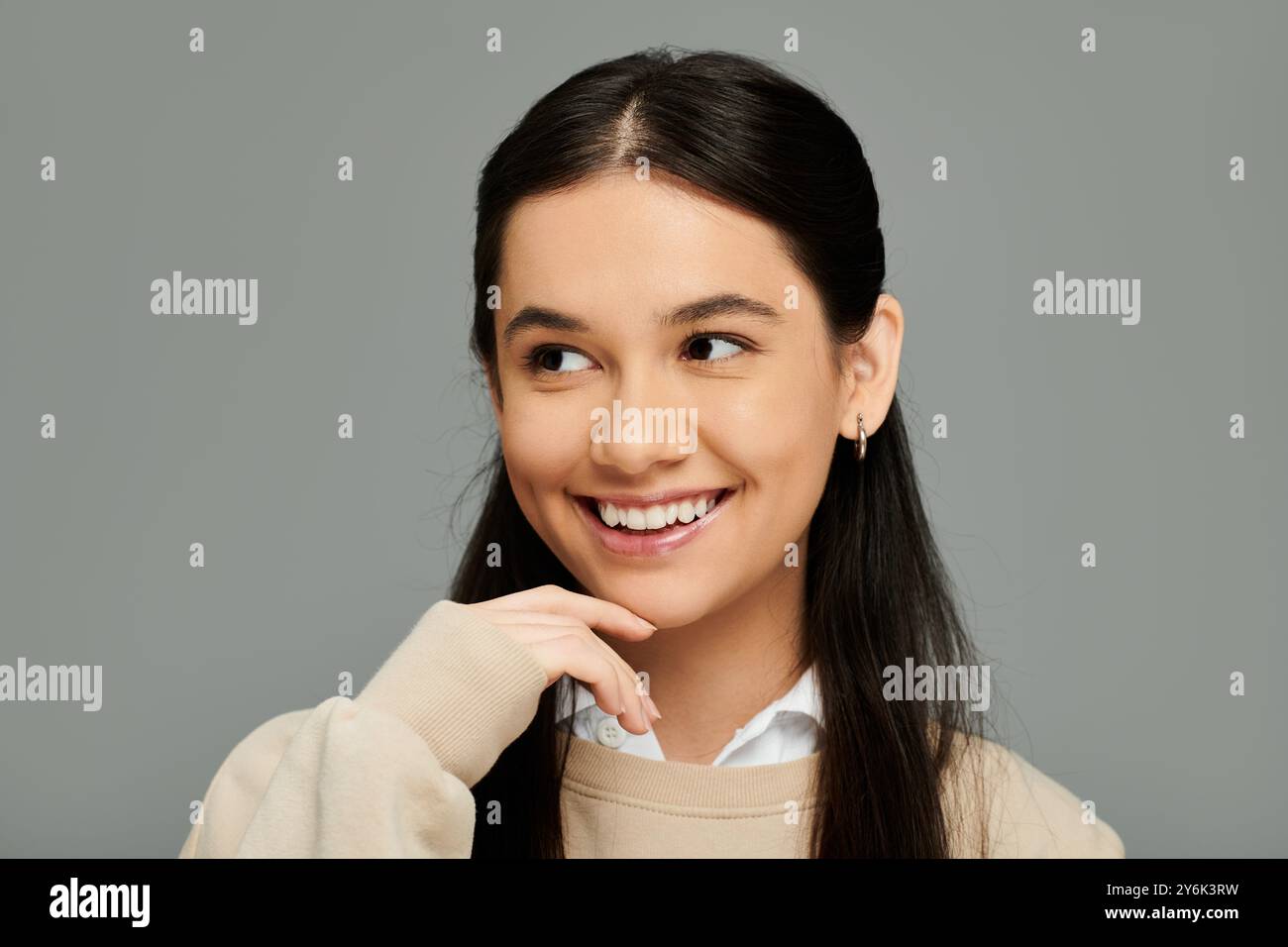 Una giovane donna sfoggia il suo outfit elegante e un sorriso luminoso, che irradia pura gioia. Foto Stock