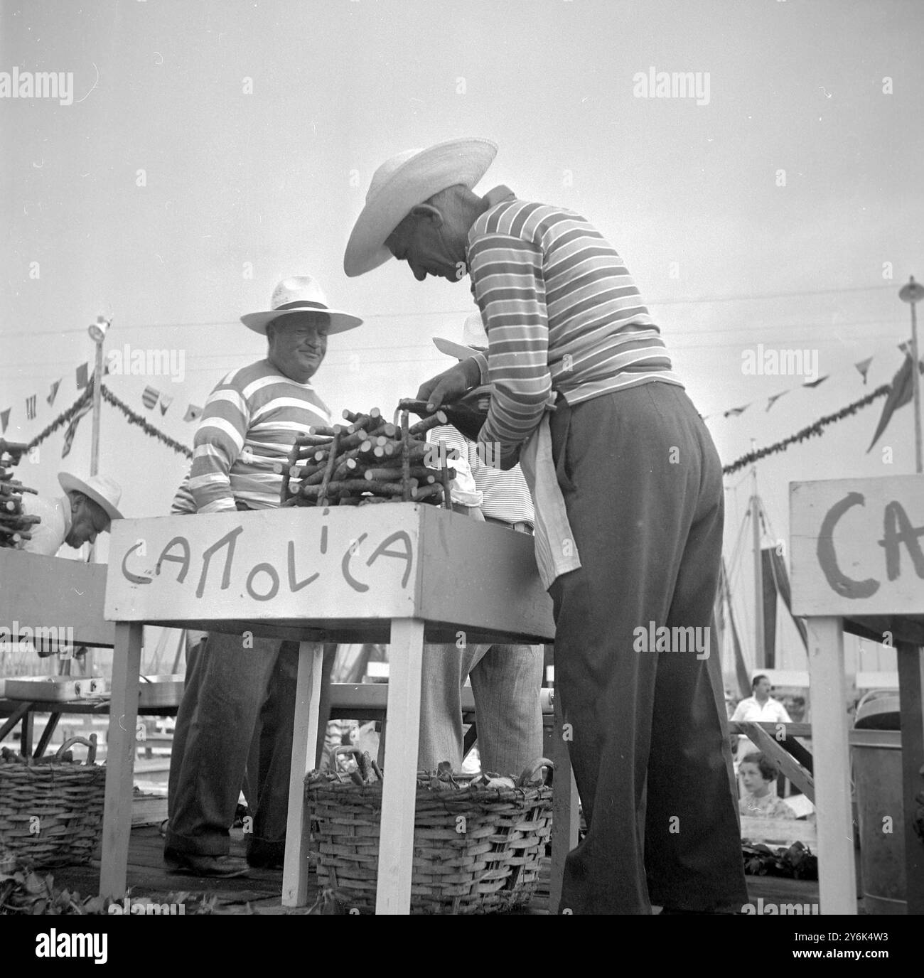Cattolica , Italia . I pescatori ringraziano il mare con un "Jamboree di pesce alla griglia" e secoli fa questo jamboree era dedicato alla "Santa madre del peschereccio naufragato" il pesce cotto viene offerto gratuitamente a chi lo vuole insieme al vino locale. Pescatori che versano lo spirito sui fuochi a legna pronti a cucinare il pesce . Luglio 1959 Foto Stock