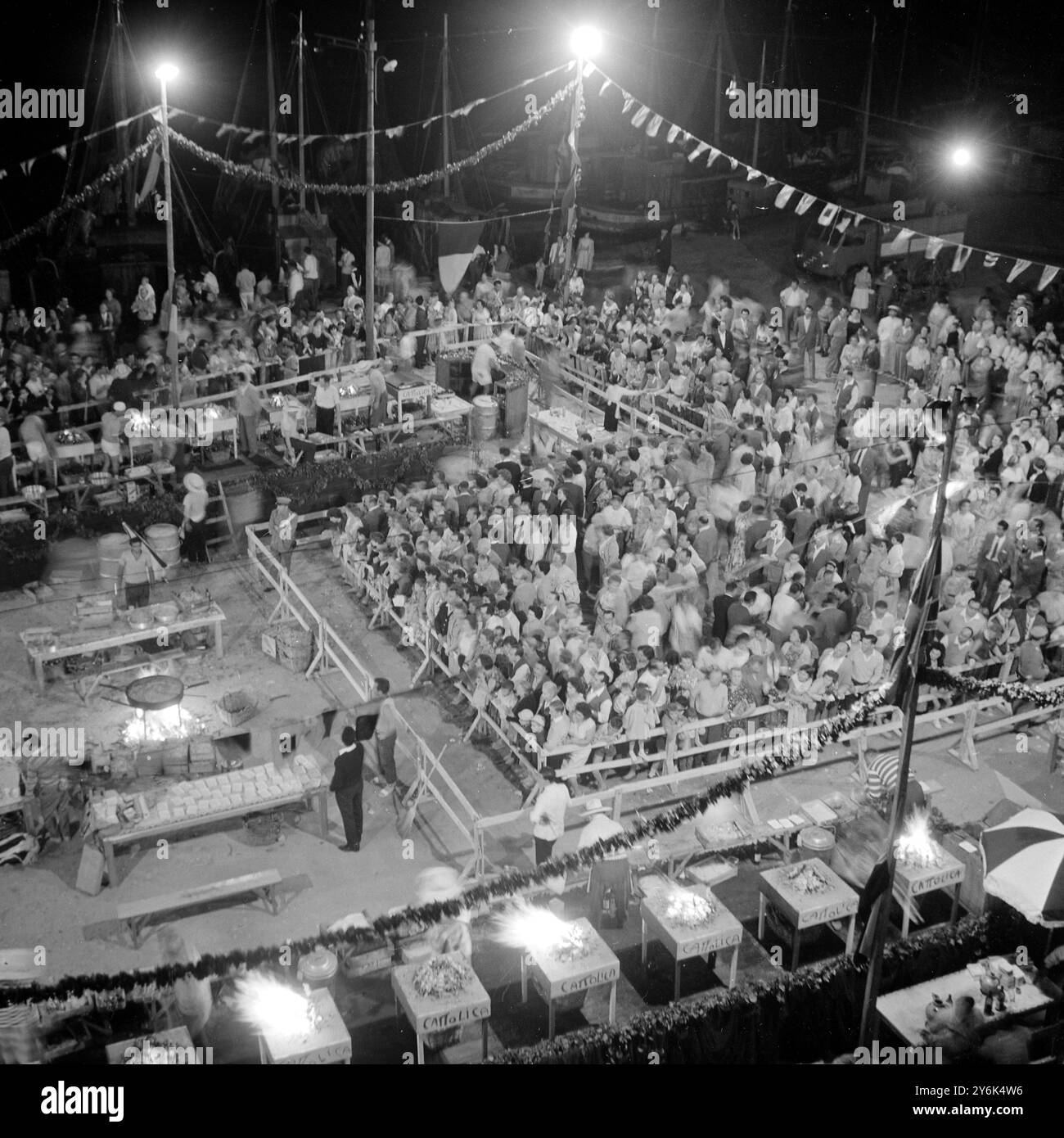 Cattolica , Italia . I pescatori ringraziano il mare con un "Jamboree di pesce alla griglia" e secoli fa questo jamboree era dedicato alla "Santa madre del peschereccio naufragato" il pesce cotto viene offerto gratuitamente a chi lo vuole insieme al vino locale. Scena notturna con folle che fanno la fila ai binari in attesa di pesce e vino gratuiti e fuochi in primo piano. Luglio 1959 Foto Stock Cattolica , Italia . I pescatori ringraziano il mare con un "Jamboree di pesce alla griglia" e secoli fa questo jamboree era dedicato alla "Santa madre del peschereccio naufragato" il pesce cotto viene offerto gratuitamente a chi lo vuole insieme al vino locale. Scena notturna con folle che fanno la fila ai binari in attesa di pesce e vino gratuiti e fuochi in primo piano. Luglio 1959 Foto Stock