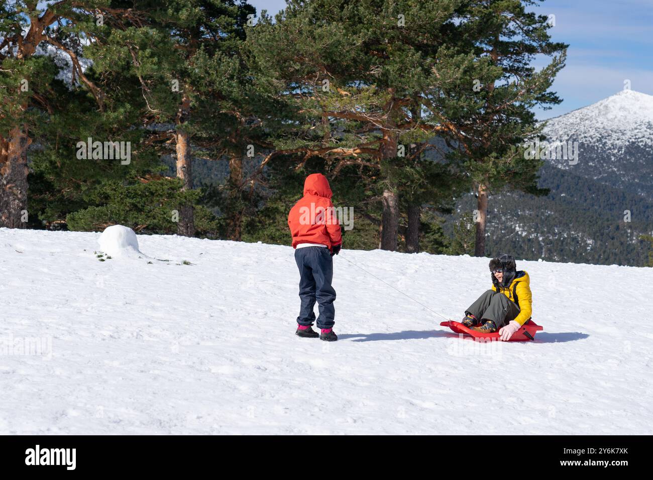 I bambini trascorrono una giornata sulla montagna innevata giocando con una slitta Foto Stock