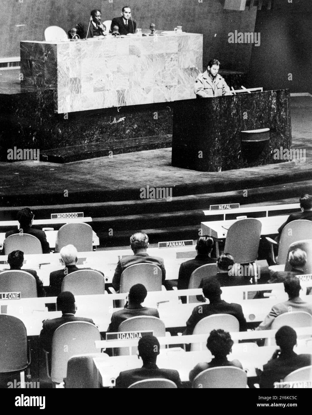 New York, Stati Uniti: Ernesto "che” Guevara, ministro dell'industria cubana e grande potenza del governo di Castro, accusa, dinanzi all'Assemblea generale delle Nazioni Unite qui oggi, che "la vita di milioni di esseri umani è costantemente minacciata e soggetta al capriccio dell'invasore americano”. Seduti dietro di lui sono da sinistra a destra, il presidente dell'Assemblea Alex Quaison-Sackey e il sottosegretario delle Nazioni Unite, C.V. Narasimhan. 11 dicembre 1964 Foto Stock