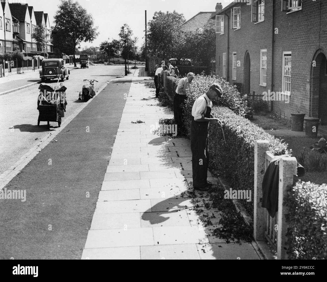 Se vivi a Downham, nel Kent, in una casa del Consiglio, le siepi sono tagliate gratuitamente. Una banda di uomini sta girando intorno alla tenuta, tagliando i margini dell'erba e tagliando le siepi, a meno che l'inquilino non l'abbia già fatto. 13 luglio 1955 foto di John Topham Foto Stock