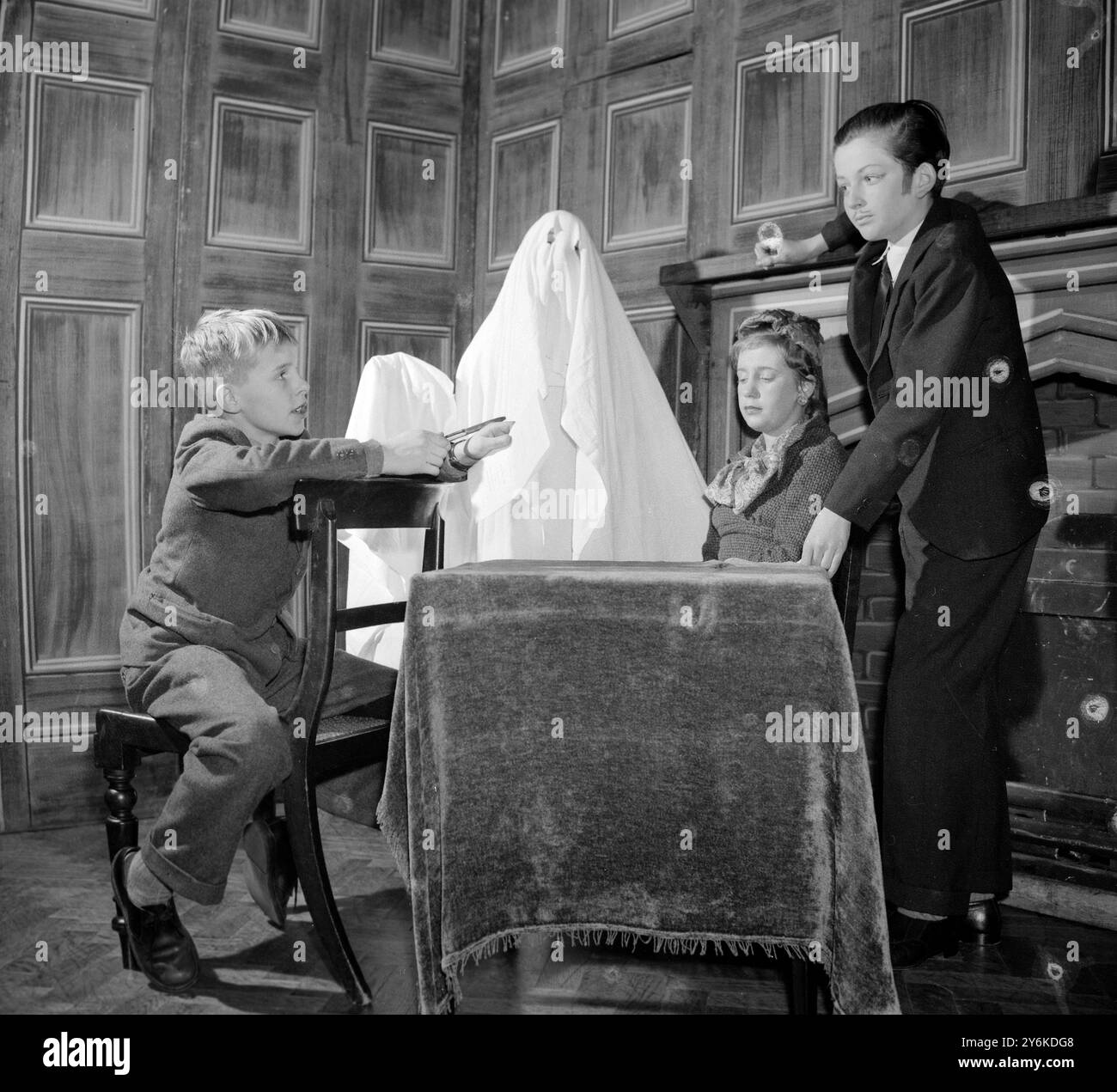 Un fantasma inquietante incombe nell'angolo durante le prove. Christopher (12 a sinistra) ha scritto l'opera teatrale THE HAUNTED HOUSE e sta anche producendo, dirigendo e recitando in essa. Qui in una scena c'è CLARISSA DICKSON WRIGHT che interpreta Anne Williams e OCTAVIAN VON HOFMANNSTHAL che interpreta James il maggiordomo. - 5 dicembre 1958. ©TopFoto Foto Stock