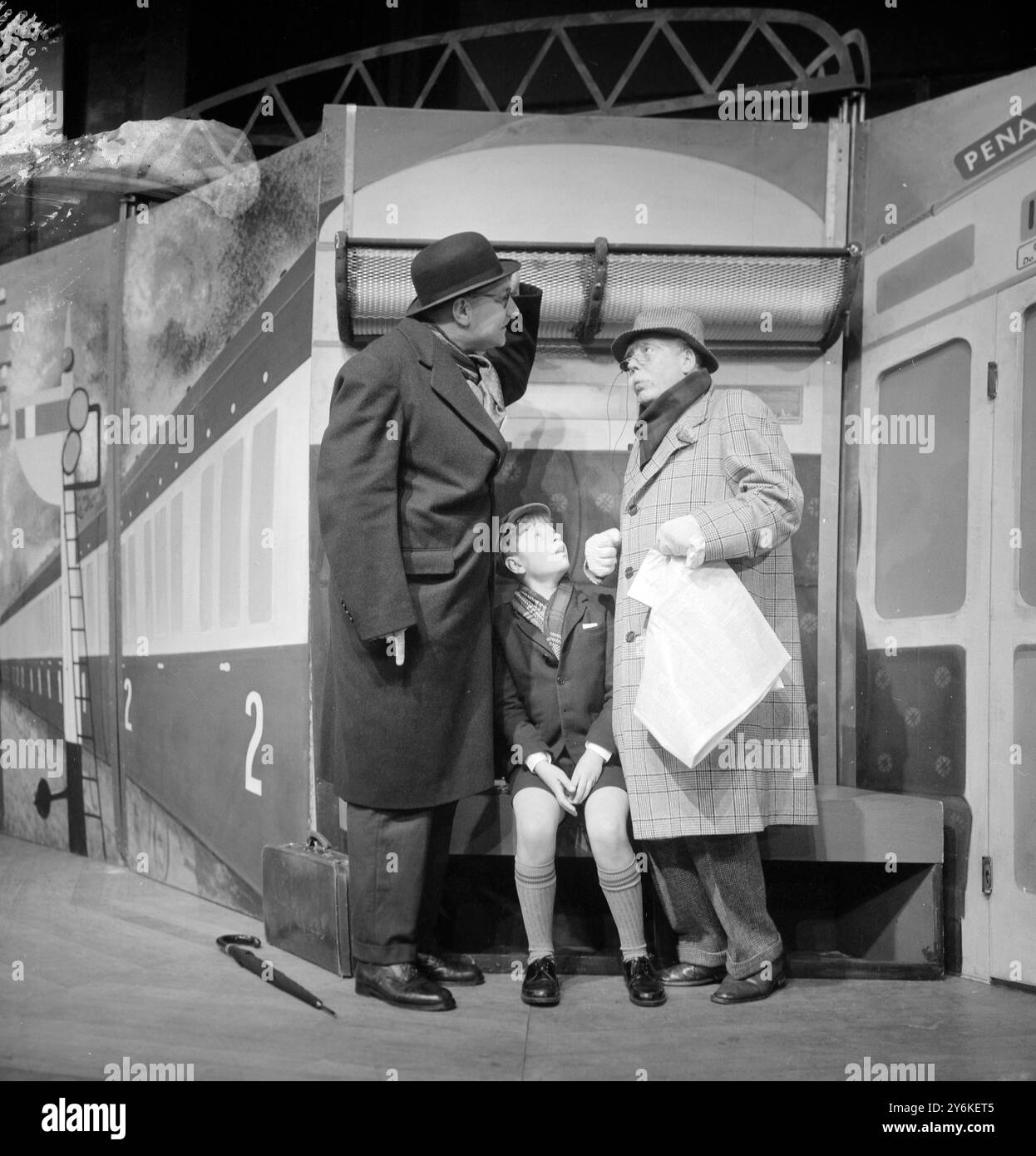 Bambini al Thameside Theatre di Londra la Sirenetta nella produzione natalizia di EMIL E I DETECTIVE, il romanzo tedesco ora adattato per il palco e dato un'ambientazione inglese. La foto mostra Emil (John Bosch) seduto in una carrozza ferroviaria ascoltando la conversazione di Mr. Grundle (Norman Scace) che interpreta il criminale che Emil e i suoi amici inseguono e Robert Webber che interpreta il vecchio. Foto scattata il 13 novembre 1960. ©TopFoto Foto Stock