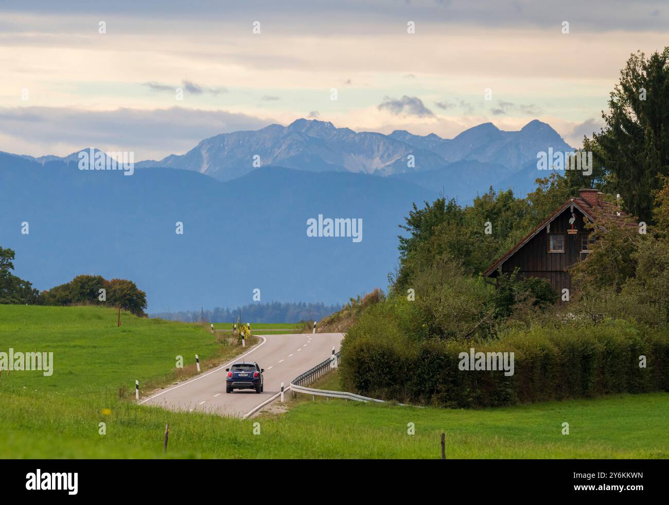 26 settembre 2024, Baviera, Münsing: Un'auto sta guidando verso sud lungo una strada di campagna vicino al lago Starnberg verso le montagne, che stanno attualmente vivendo una forte tempesta di foehn. Foto: Peter Kneffel/dpa Foto Stock