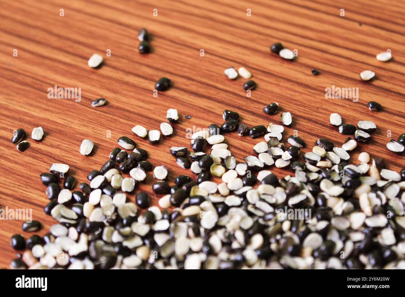 Split Black Lentil conosciuto anche come Black Gram, Black Urad dal, Vigna Mungo, Urad Bean su fondo in legno marrone Foto Stock