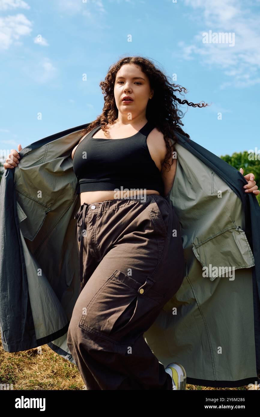 Una donna sicura di sé e di taglia si diverte nella bellezza di un campo illuminato dal sole, circondato dalla natura. Foto Stock