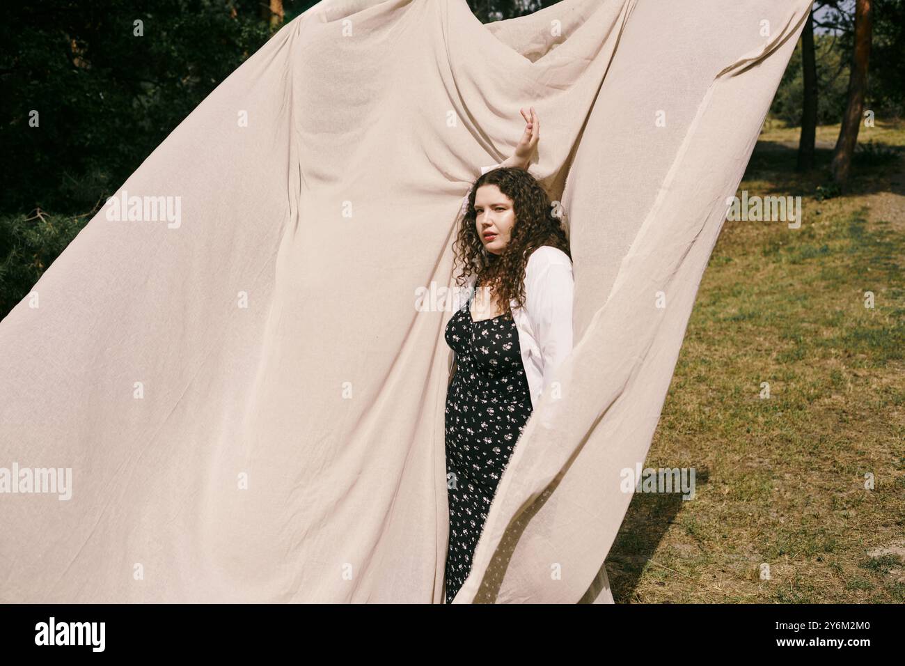 Una donna sicura di sé e taglia si trova graziosamente in un campo soleggiato, abbracciando la sua bellezza. Foto Stock