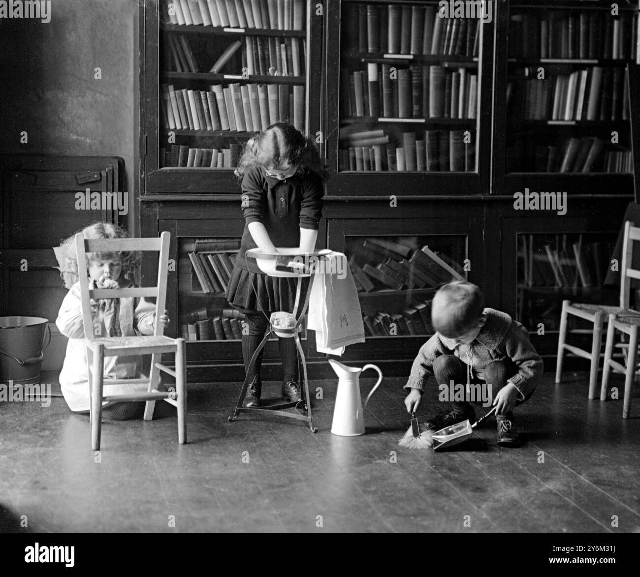 Montessori School presso Golders Green, North West London. Bambini che giocano - fingono di fare le pulizie. Spazzolate il pavimento con una padella e una spazzola, spolverate una sedia e lavate alcuni panni in un supporto per lavare. Foto Stock