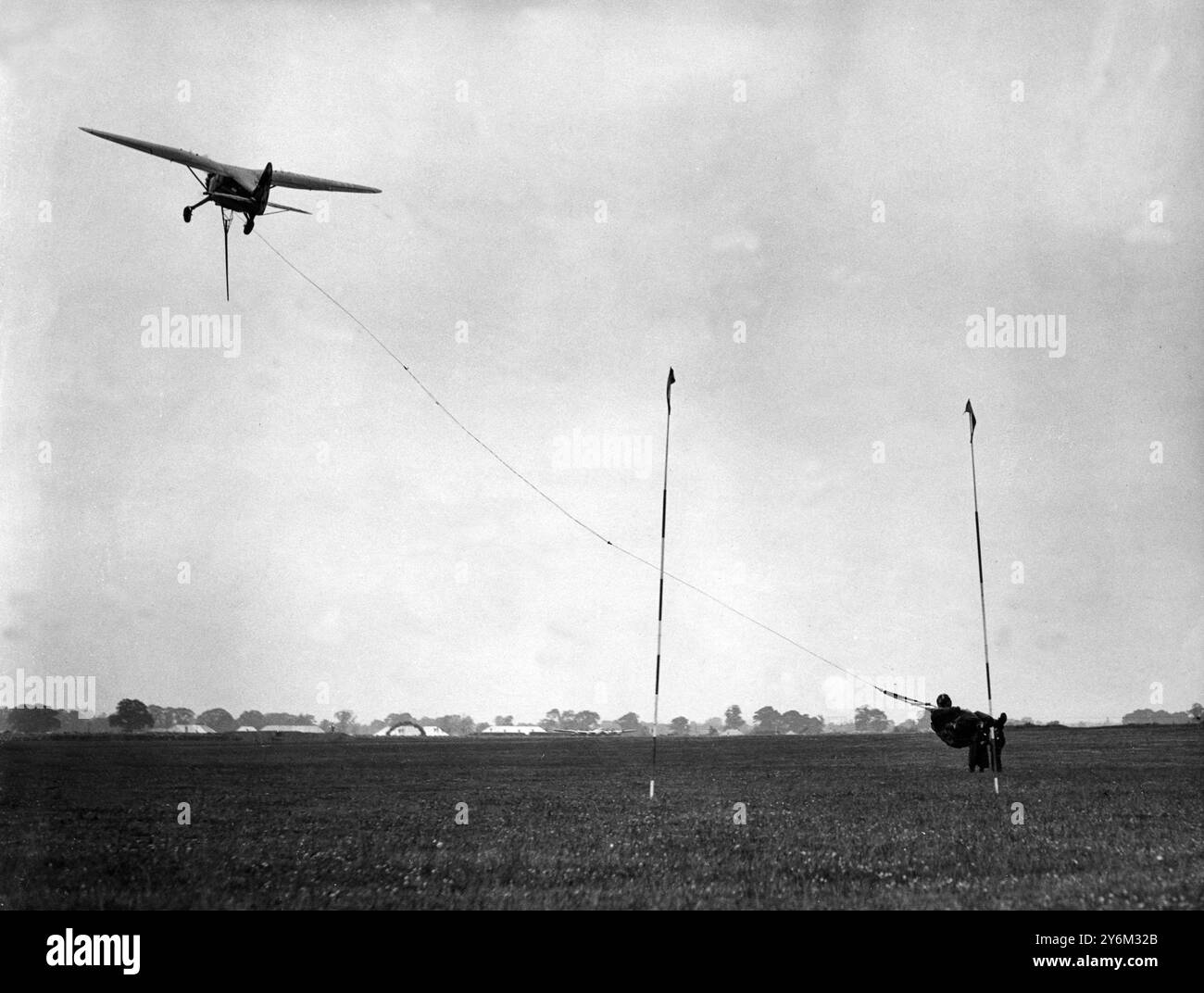Michael Cain, indossando un'imbracatura speciale, viene prelevato con una linea della macchina Stinson Reliant che è stata utilizzata negli Stati Uniti per ritirare la posta. Questo è stato uno dei tanti eventi spettacolari del Gatwick Air Pageant. 10 luglio 1948. Foto Stock