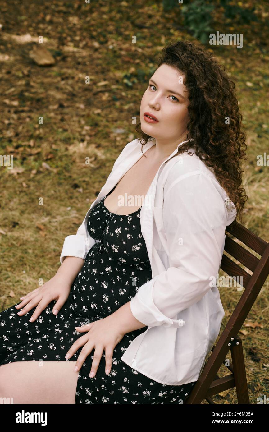 Una bella donna di grandi dimensioni siede graziosamente in un campo, circondato dalla natura vibrante bellezza. Foto Stock Una bella donna di grandi dimensioni siede graziosamente in un campo, circondato dalla natura vibrante bellezza. Foto Stock