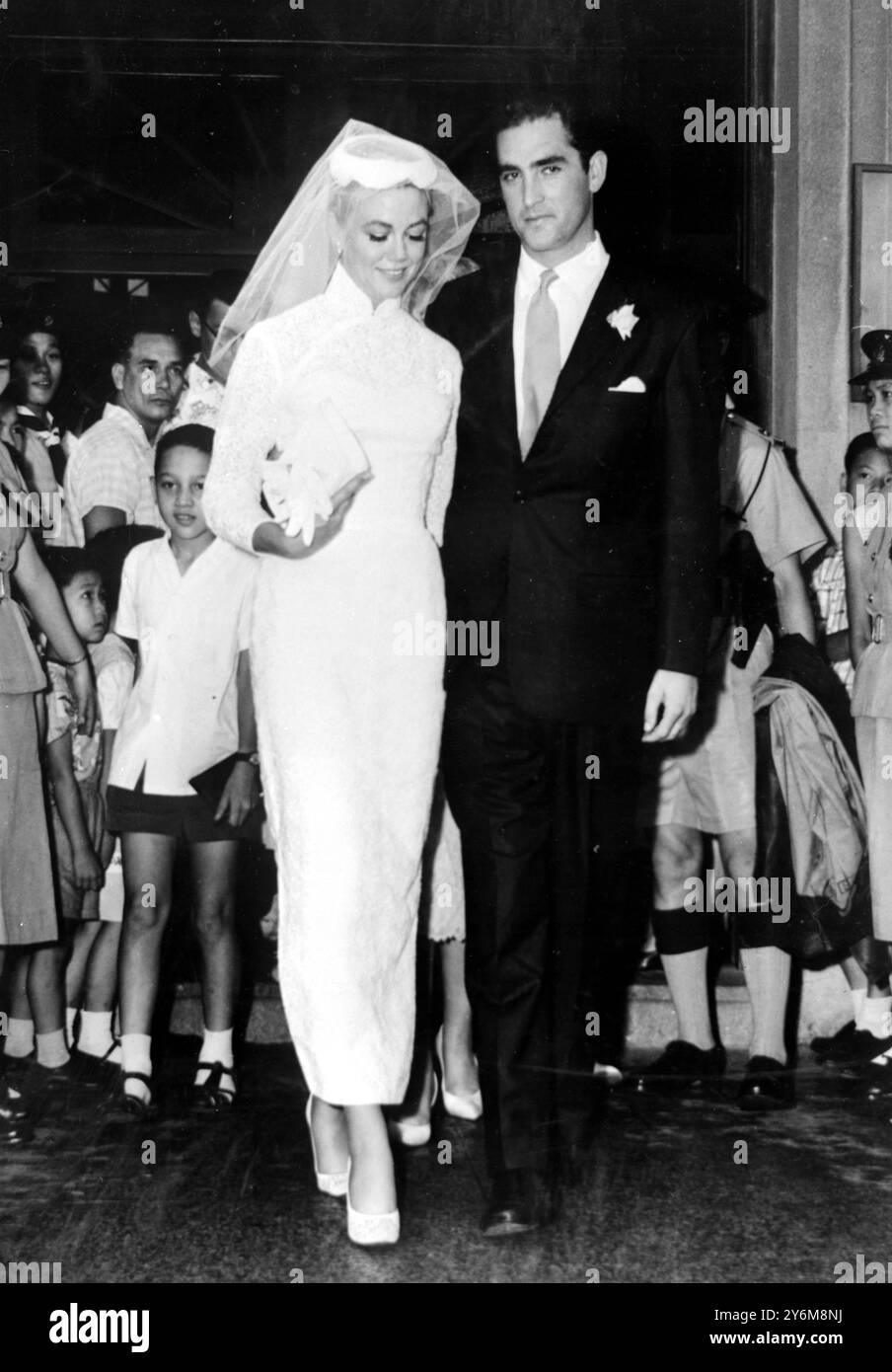 Hong Kong: Jacques Bergerac, ex marito di Ginger Rogers, ha un bacio per la sua nuova sposa il film americano attrice Dorothy Malone dopo il loro matrimonio a Hong Kong interpretato da padre Camelo Orlando alla chiesa cattolica romana di Santa Teresa. Bergerac ha cercato una dispensa speciale dal governatore per il normale periodo di attesa di quindici giorni, che avrebbe permesso loro di sposare immediatamente Bergerac, Miss Malone e la madre di Miss Malone sono arrivati a Hong Kong Tokyo di recente, dove Miss Malone ha girato un film il 28 giugno 1959 Foto Stock