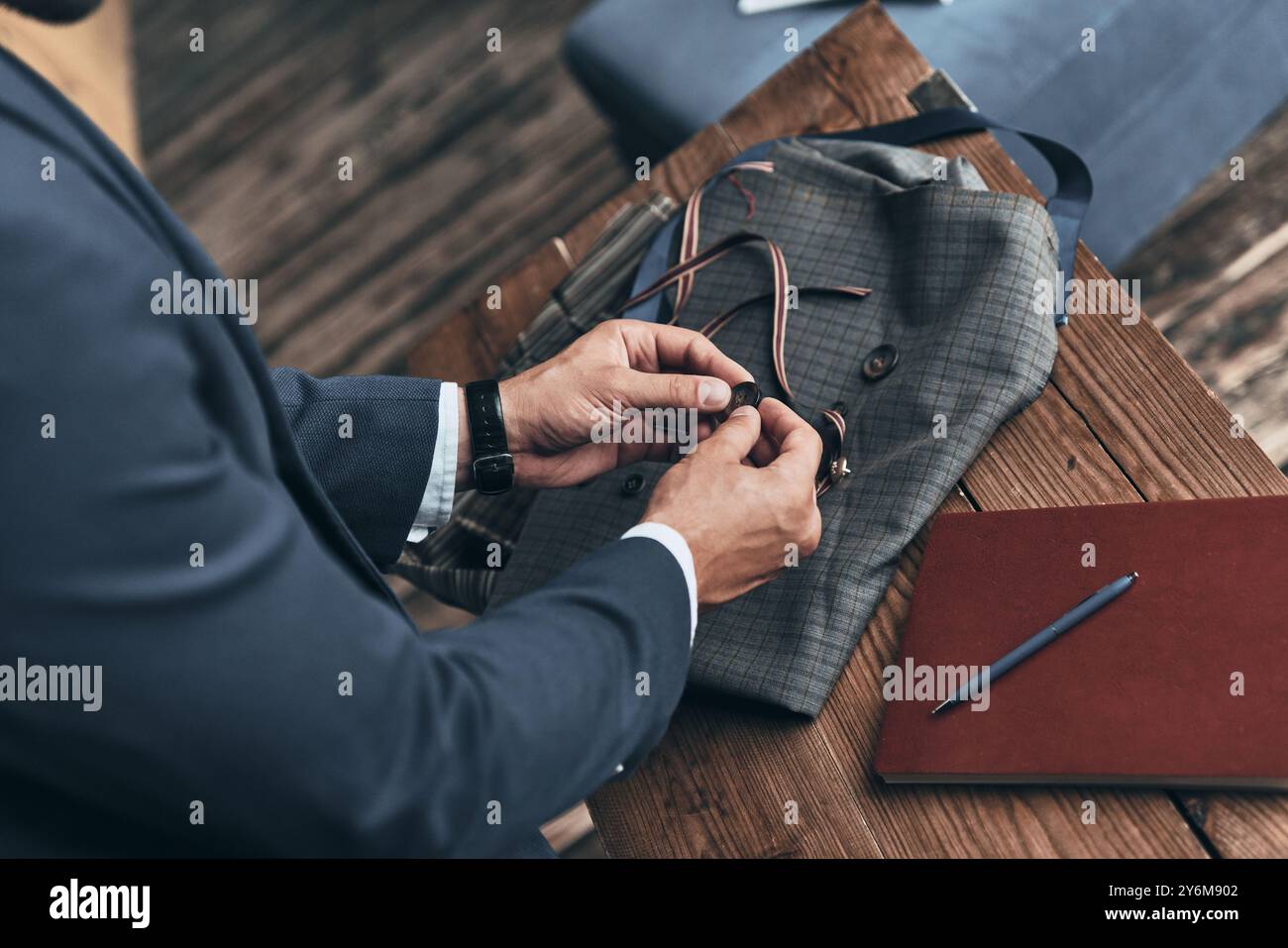 Sto cercando di scegliere il migliore. Vista ravvicinata dall'alto dello stilista di moda che sceglie i bottoni mentre lavora in uno studio di design di abbigliamento Foto Stock