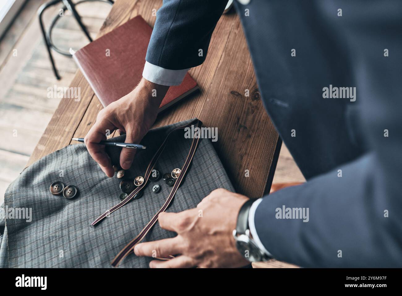 Giovani perfezionisti. Primo piano dello stilista di moda che sceglie il campione di tessuto mentre lavora nello studio di design dell'abbigliamento Foto Stock