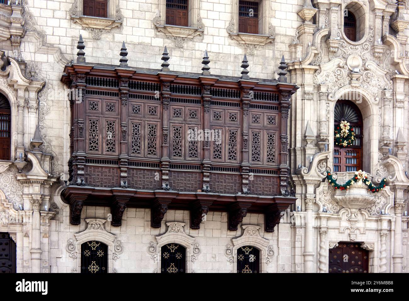Primo piano di una dettagliata facciata coloniale con un balcone in legno ornato e decorazioni festose a Lima, Perù. Cattura l'eleganza e la storia Foto Stock