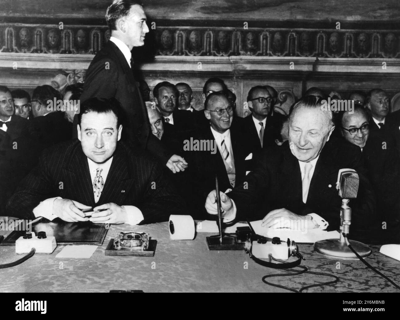 Trattato di Roma sei governi europei si sono impegnati a Roma per unirsi in un blocco commerciale senza dogana. Nell'antico municipio di Roma, i leader di 160 milioni di europei firmarono documenti che alla fine potrebbero legarsi a una potente unione economica. I sei paesi coinvolti nel patto sono la Germania (Ovest), la Francia, l'Italia, il Belgio, l'Olanda e il Lussemburgo. Foto: Il signor Edgar Faure di Francia, a sinistra, guarda il cameraman mentre il tedesco Herr Adenauer firma il patto per la repubblica federale di Germania. 25 maggio 1957 Foto Stock
