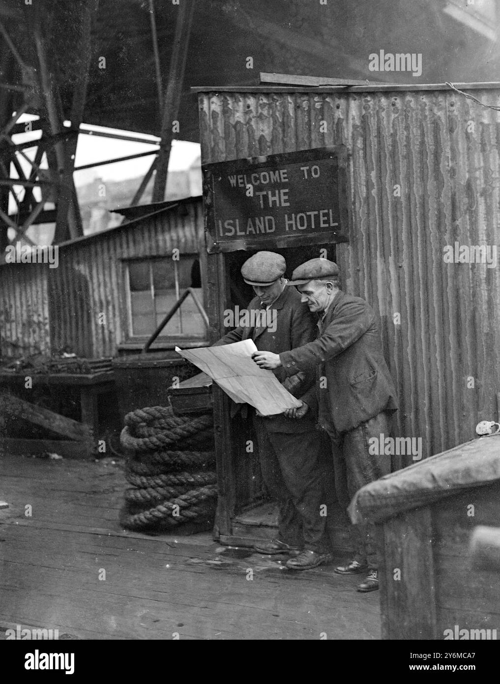 "Benvenuti all'hotel dell'isola" è l'iscrizione ironica sopra l'ingresso di una capanna su una piattaforma nel mezzo del Tamigi presso il ponte Waterloo. La capanna è usata come ufficio dal signor F. Emerson, impegnato nei lavori di demolizione. 28 novembre 1935 Foto Stock