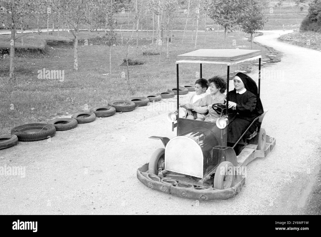 Perugia, Italia: Questi bambini potrebbero essere sulla strada giusta con questo tipo di conducente. Durante una visita alla "città della domenica" (città italiana dei ragazzi, una suora, porta due bambini in auto sulla pista di go-kart... Forse i grossi paraurti non sono necessari in questo viaggio... ma chi può dire cosa potrebbe succedere ... se il bug corse capita di mordere.. 30 settembre 1968 Foto Stock