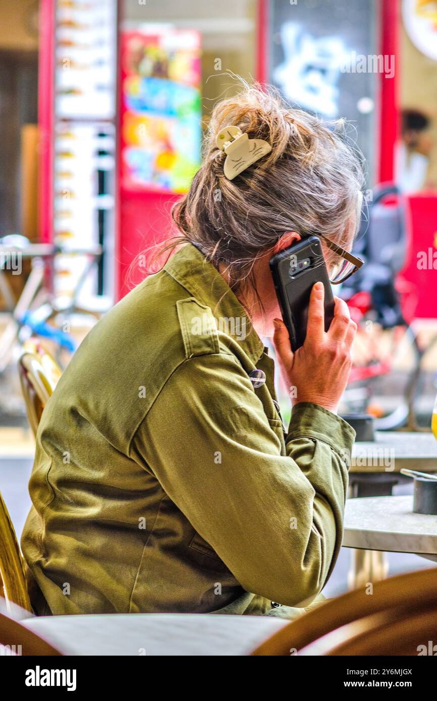 Una donna sedeva al tavolo del caffè parlando al telefono cellulare - Tours, Indre-et-Loire (37), Francia. Foto Stock