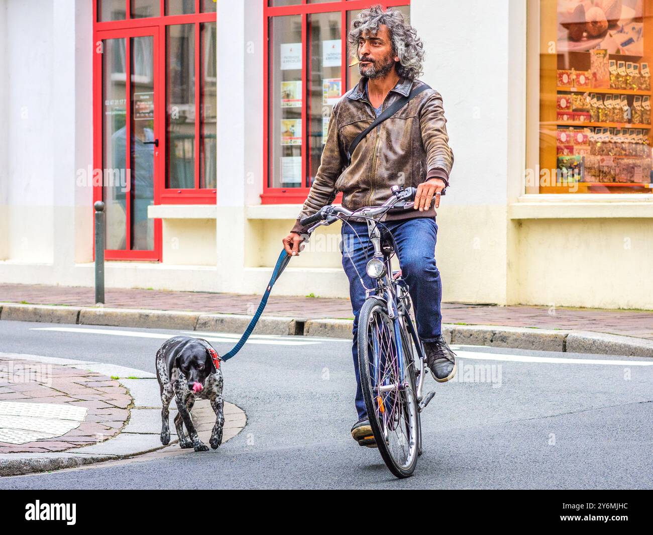 Uomo fresco con capelli lunghi in bicicletta che porta il cane per l'esercizio fisico nel centro della città - Tours, Indre-et-Loire (37), Francia. Foto Stock