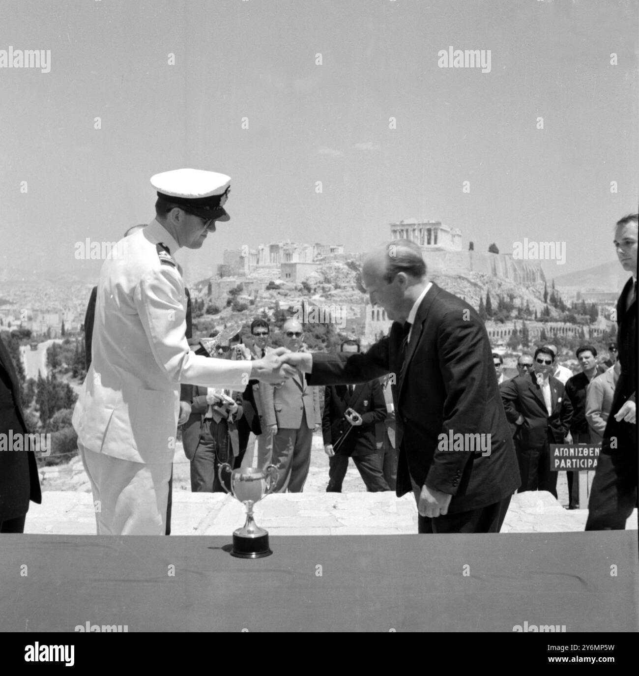 Atene, Grecia, con l'Acropoli che fornisce uno sfondo adeguato il pilota tedesco di Rally E. Bohringer (a destra) stringe la mano al principe ereditario Costantino di Grecia prima di raccogliere il suo trofeo per essere arrivato primo nella classifica generale del recente Rally dell'Acropoli. Con P... Secondo conducente Lang, Bohringer, visto lì durante la cerimonia di presentazione di ieri ha avuto anche il primo posto nella classe per le auto oltre 2, 001 c.c. 31 maggio 1962 Foto Stock