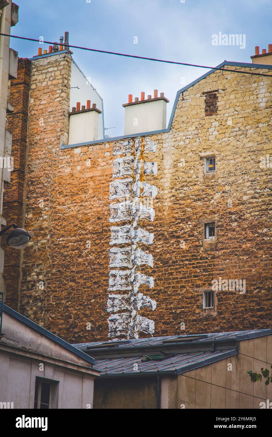 Francia, Parigi. Street art, spine su un muro di mattoni sul retro di un edificio Foto Stock