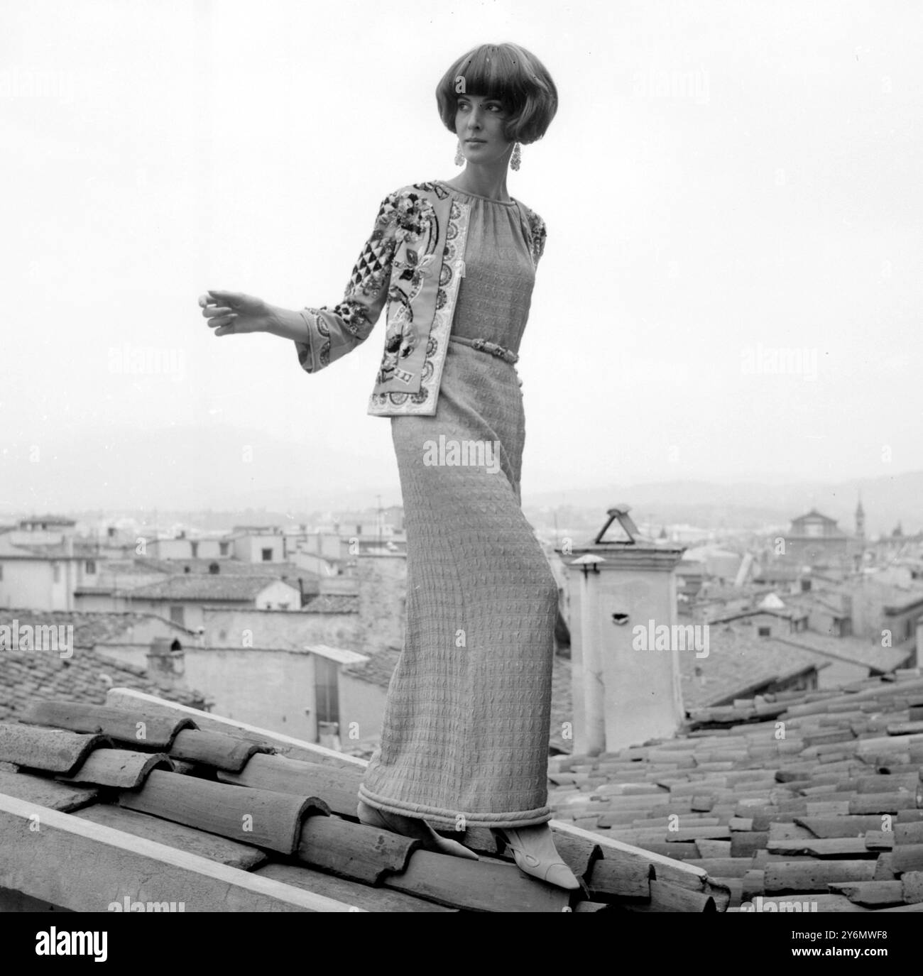 Una creazione di Emilio Pucci modellata su un tetto a Firenze. Si tratta di un abito da sera in seta color geranio e di una minuscola giacca ricamata che compare nella sua collezione autunnale del 1965. Il contrasto è pittoresco tra l'abito unicolore e la piccola giacca multicolore ricamata. Un piccolo drappo sul colletto senza fiocchi, poi una cintura dorata rompe l'elegante uniformità dell'abito che ha un ampio orlo con rifinitura alla fine del 5 agosto 1965 Foto Stock