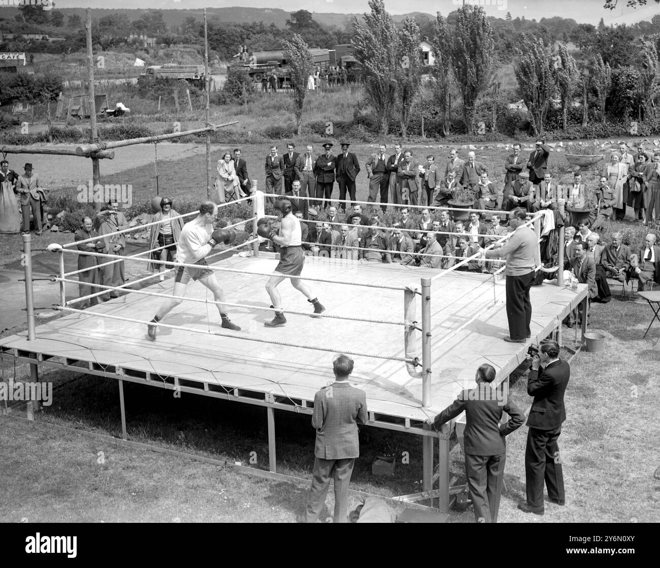 Visitatori del Barley Mow di Betchworth, Surrey. Aiuta a portare qualcosa dell'atmosfera di White City ai quartieri di allenamento di Freddie Mills lì oggi (lunedì) mentre Mills (indossando la guardia del capo) si allena con Leeds Boxer al Robinson sul ring all'aperto. Mills, campione mondiale dei pesi massimi leggeri, sta ora mettendo il tocco finale al suo allenamento per la sua lotta contro il campione britannico, Empire ed europeo dei pesi massimi Bruce Woodcock al White City Stadium (Londra il 2 giugno). I titoli di Woodcock saranno in gioco. Tra gli spettatori della falesia di Barley oggi c'erano ex militari disabili dell'Hospita di St. Mary Foto Stock