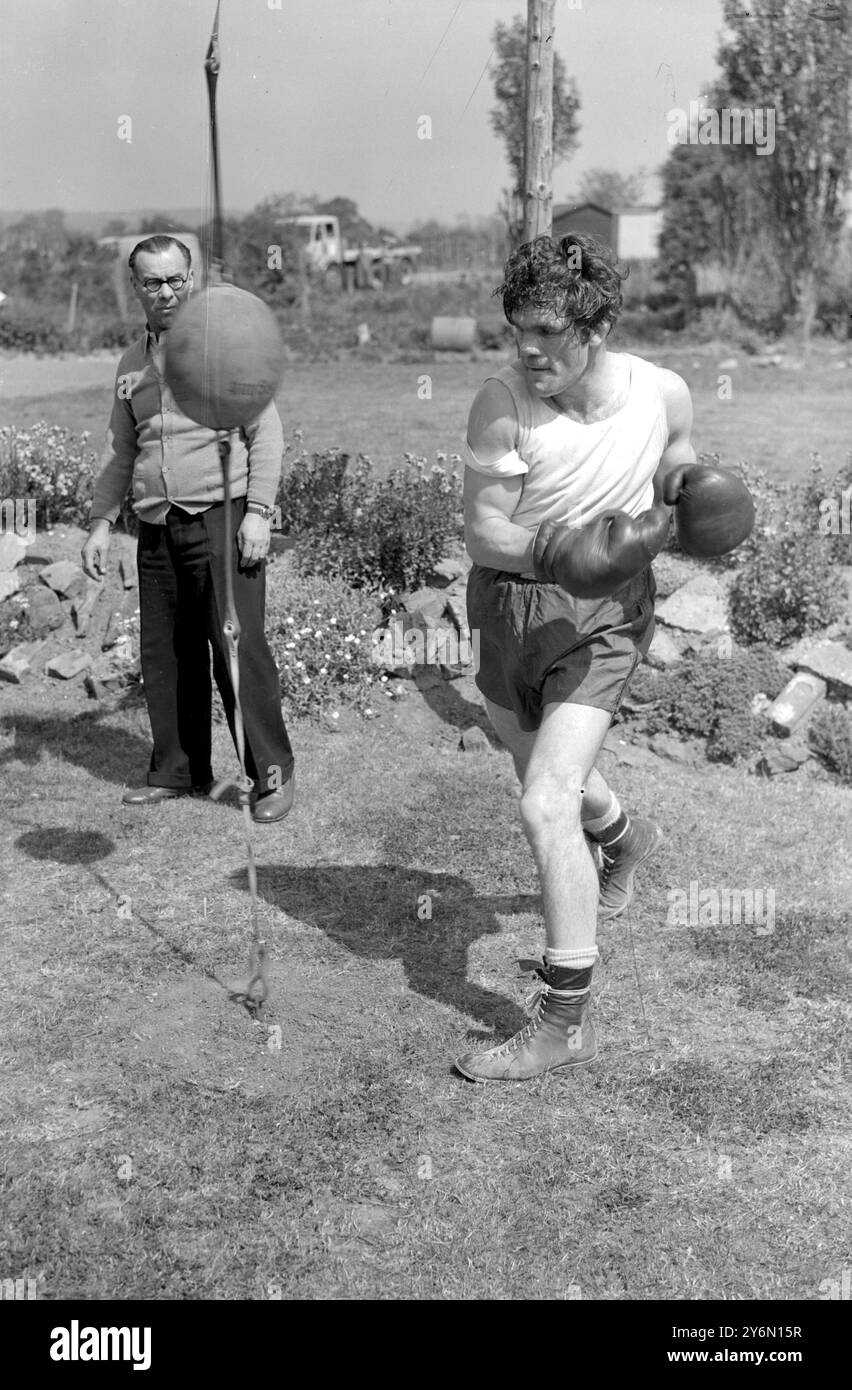 Tousled Freddie Mills, campione mondiale dei pesi mediomassimi, si aggira al pugno all'aria aperta al campo da badley, Betchworth, Surry, dove i mulini si trovano ora nella fase finale di allenamento per la sua lotta con Bruce Woodcock al White City Stadium di Londra, il 2 giugno.a guardare c'è l'allenatore di Nat Sellars Mills. 18 maggio 1949 Foto Stock