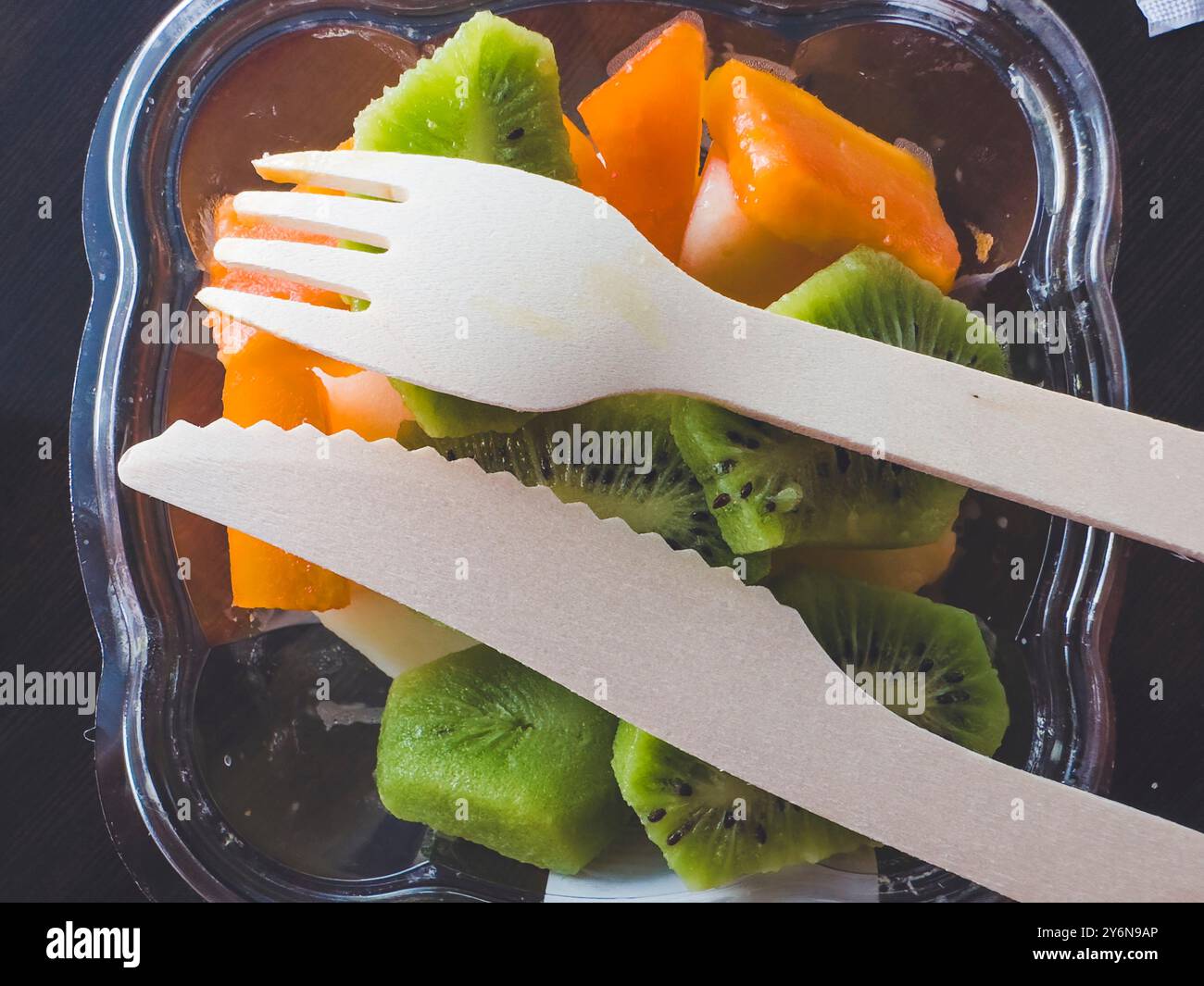 Posate di legno poste sulla frutta in un contenitore di plastica Foto Stock