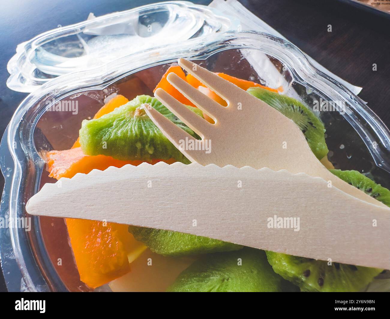 Posate di legno poste sulla frutta in un contenitore di plastica Foto Stock