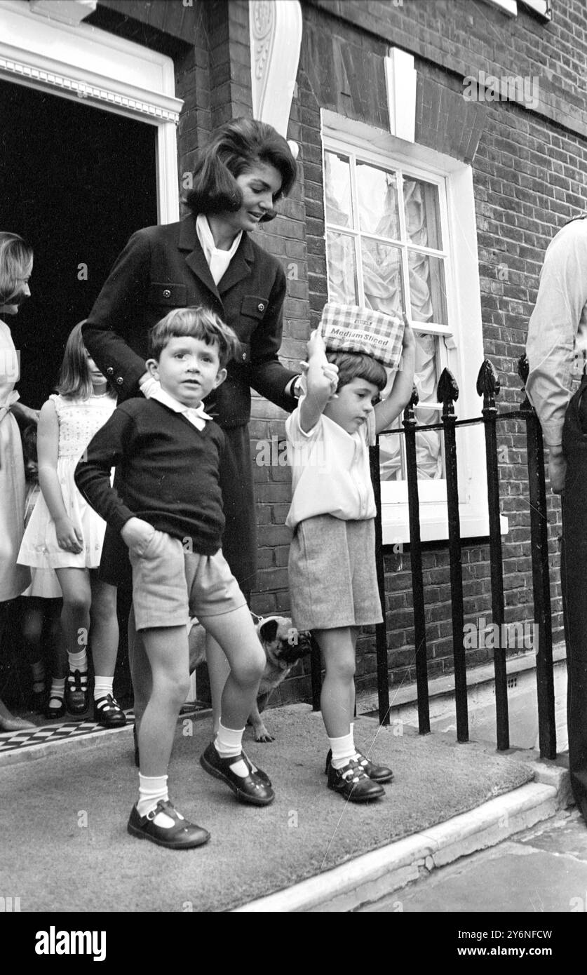 Londra: Sperando in un'opportunità per dare da mangiare agli uccelli nel London Park ... Maestro John Kennedy, di 4 anni. Con una pagnotta piena di pane affettata sulla testa, stava partendo con la madre, la signora Jacqueline Kennedy, vedova del defunto presidente degli Stati Uniti, e il maestro Anthony Radziwill, suo cugino, per una breve gita turistica che includeva una visita a Buckingham Palace. 13 maggio 1965 Foto Stock