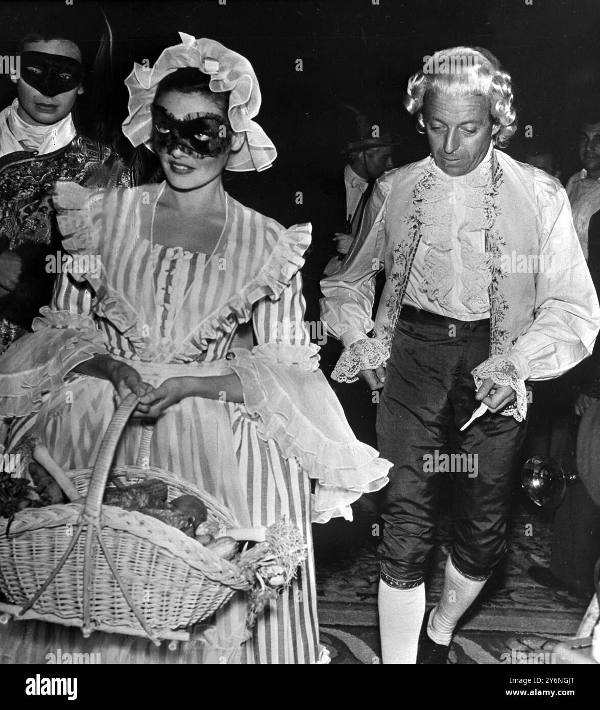 La grande festa veneziana. La favolosa festa di riscaldamento della casa organizzata dal milionario spagnolo Don Carlos de Bestegui Y Iturbi nel suo nuovo palazzo sul Canal grande di Venezia, ha attirato ospiti riccamente vestiti da tutta Europa. Dopo aver ballato fino all'alba, i mille o più ospiti sono stati riportati ai loro hotel a Gondola. Vino e cibo venivano anche dati alle folle nelle strade che avevano il loro partito fuori dal palazzo. Gene Tierney accompagnato dal barone italiano D'avanzo alla festa veneziana. 5 settembre 1951 Foto Stock