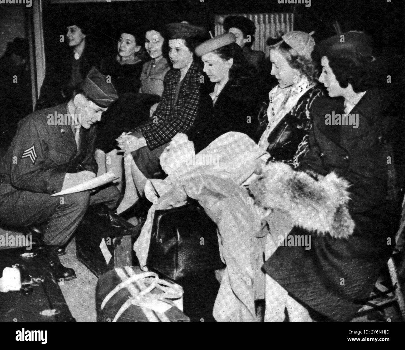 Gi spose in viaggio per noi al campo di transito, un sergente americano che controlla le identità delle spose gi nella prima fase del loro viaggio per ricongiungersi ai loro mariti. Febbraio 1946 Foto Stock