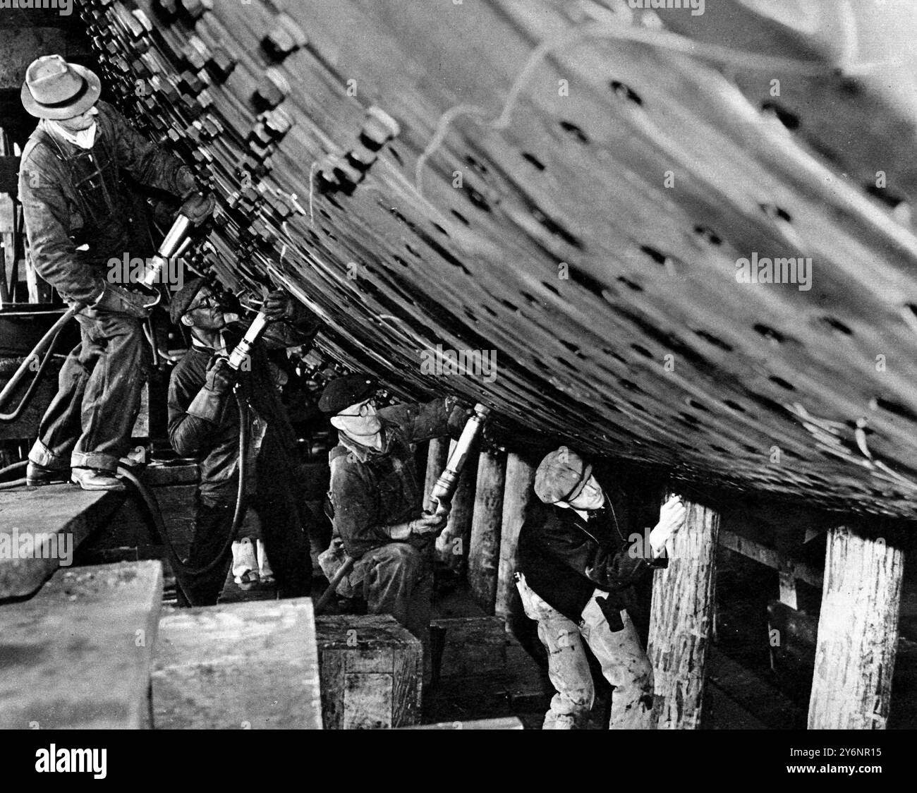 La più grande fodera costruita in America la fodera da 30.000 tonnellate "America" prende forma sulle scorte: Operai che sostituiscono i bulloni che vengono temporaneamente utilizzati per tenere insieme le piastre, con rivetti svasati a filo con le piastre in modo da presentare la minore resistenza all'acqua. ©2004 Topfoto Foto Stock