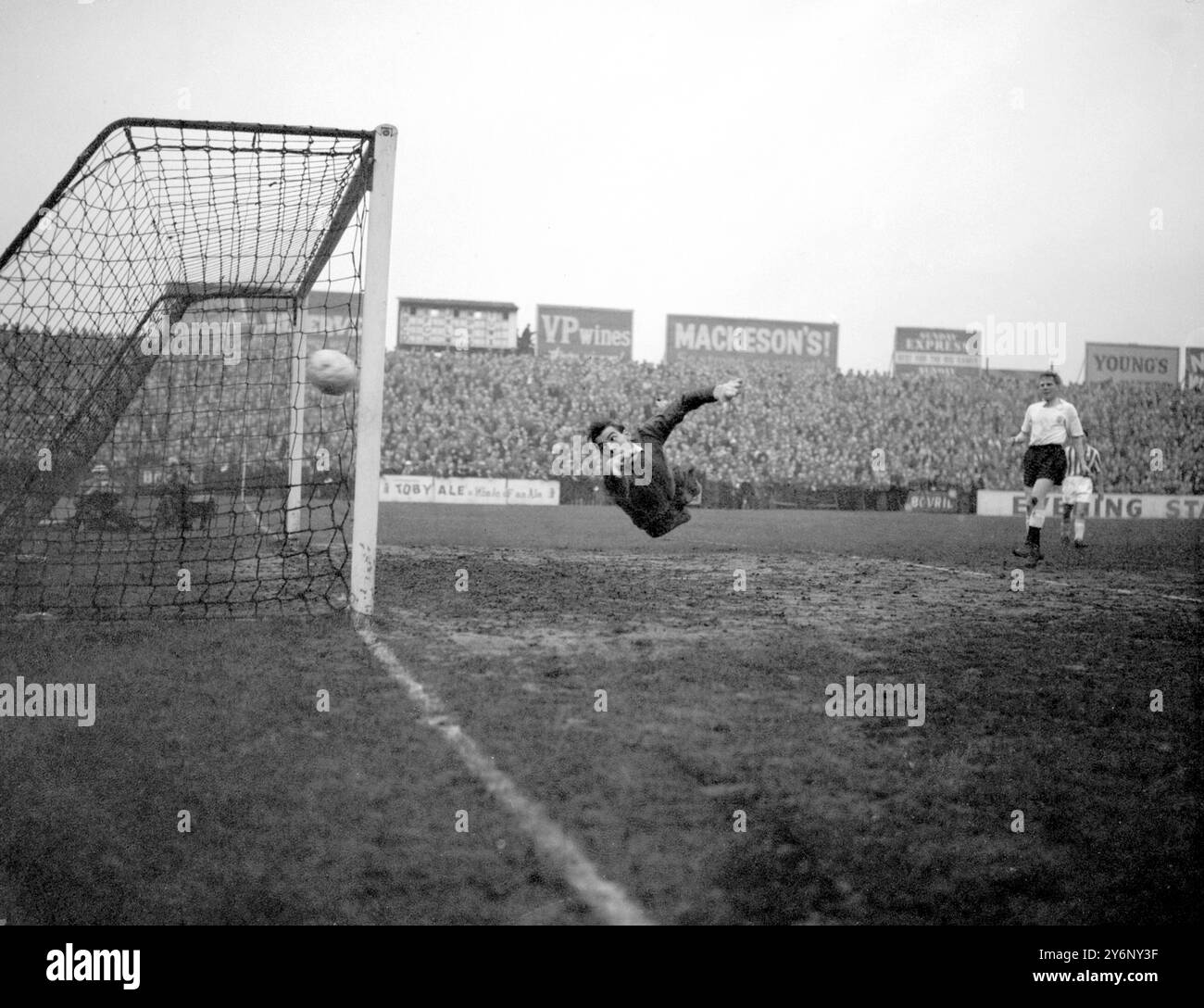 Londra: Il portiere del Fulham, Macedo, fa un salto in aria attraverso il suo gol nel tentativo di salvare la palla da un attacco di Brighton e Hove Albion durante la partita Fulham contro Brighton League Division II al Craven Cottage. 26 dicembre 1958 Foto Stock