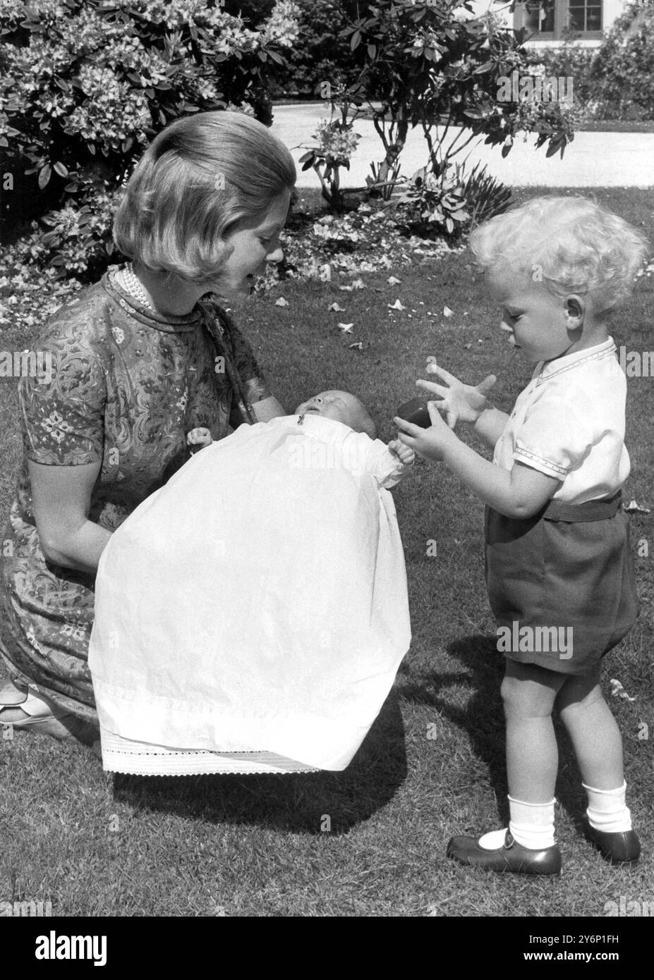 Il conte biondo di St Andrews è ansioso di giocare con la sua nuova sorella, ma non si rende conto di essere troppo giovane per partecipare ai suoi giochi nei giardini incantevoli della loro casa. Coppins, Iver, Buckinghamshire. La bambina, Lady Helen Windsor, è tra le braccia di sua madre, la duchessa di Kent. Queste sono le prime foto della bambina che verrà battezzata Helen Marina Lucy nella cappella privata del Castello di Windsor domani (sabato). Lady Helen, tredicesima in linea di successione al Trono, nacque a Coppins il 28 aprile. Il conte di St. Andrews avrà due anni il 26 giugno. 5 giugno 1964 Foto Stock